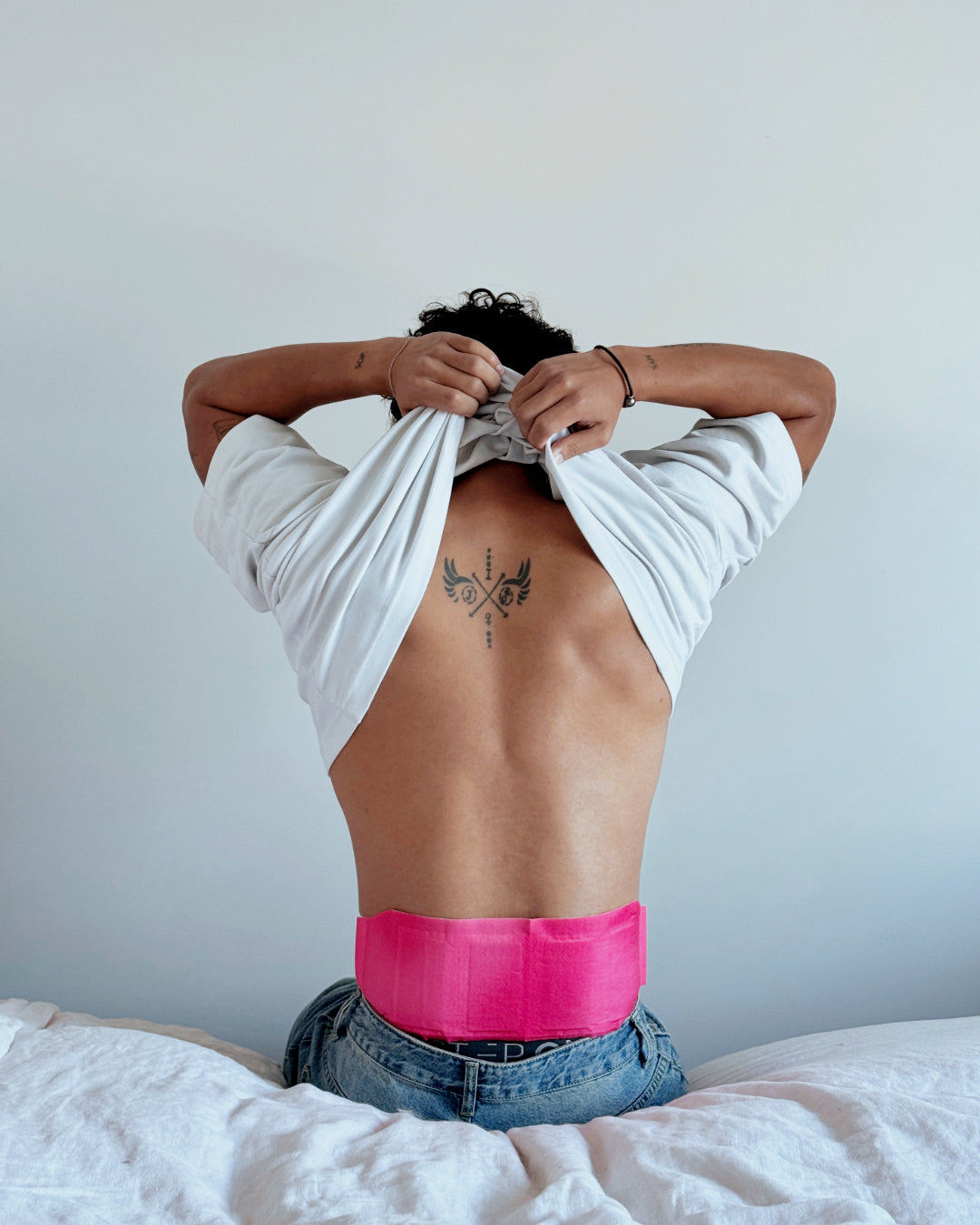 Hotstuff HydroHeat Back Relief patch worn while stretching arms in bed, demonstrating comfortable back pain relief.