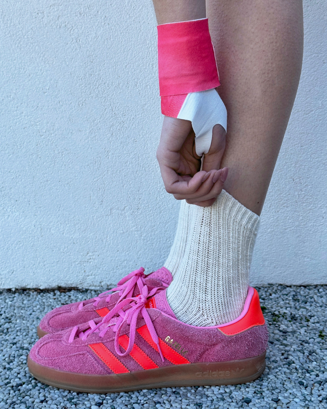Hotstuff Hydroheat Wrist Relief wrap in pink, worn on wrist with pink sneakers and white socks.